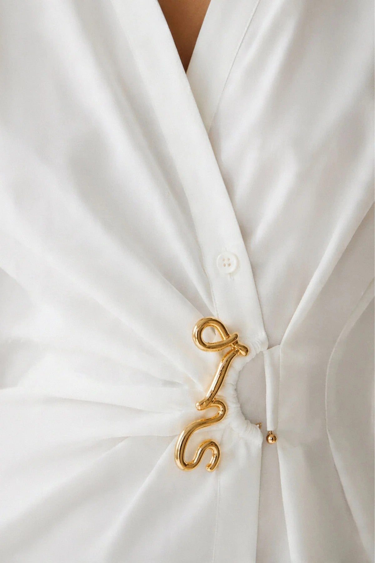 Close-up da pregadeira dourada na camisa